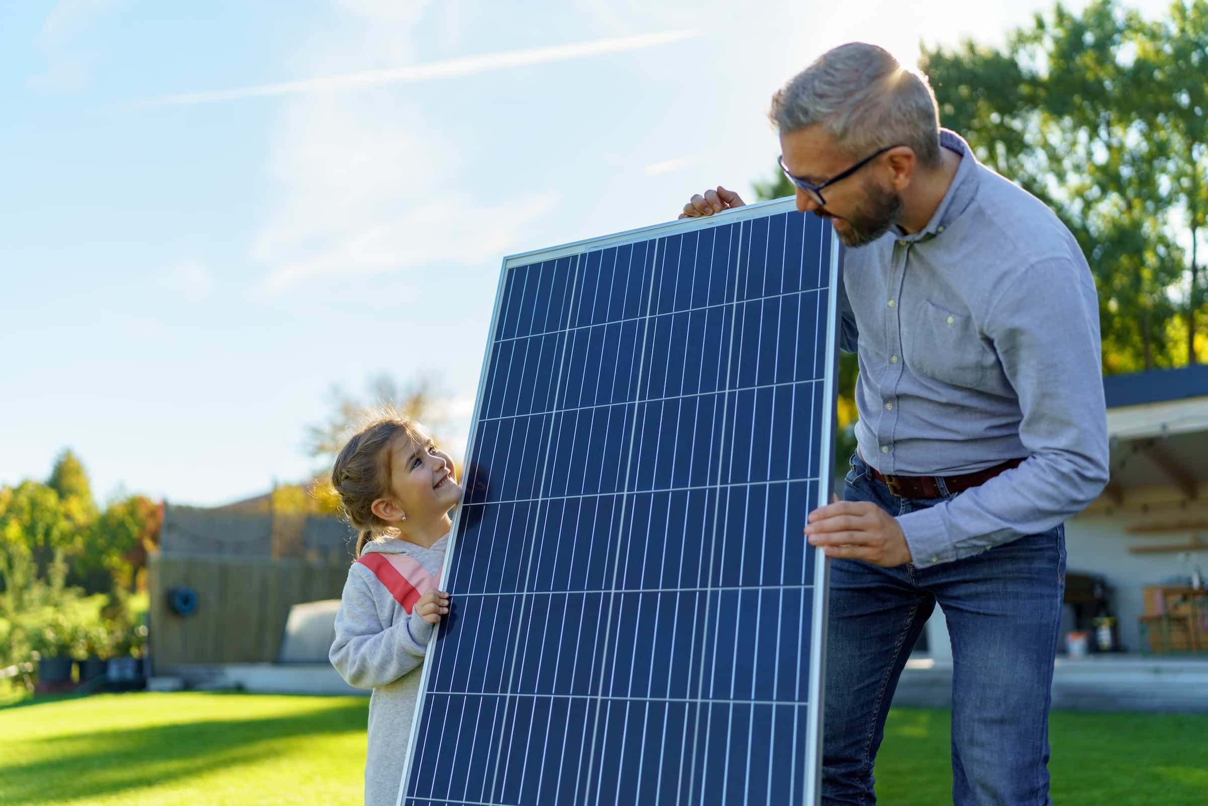 Father and daughter holding solar panel together
