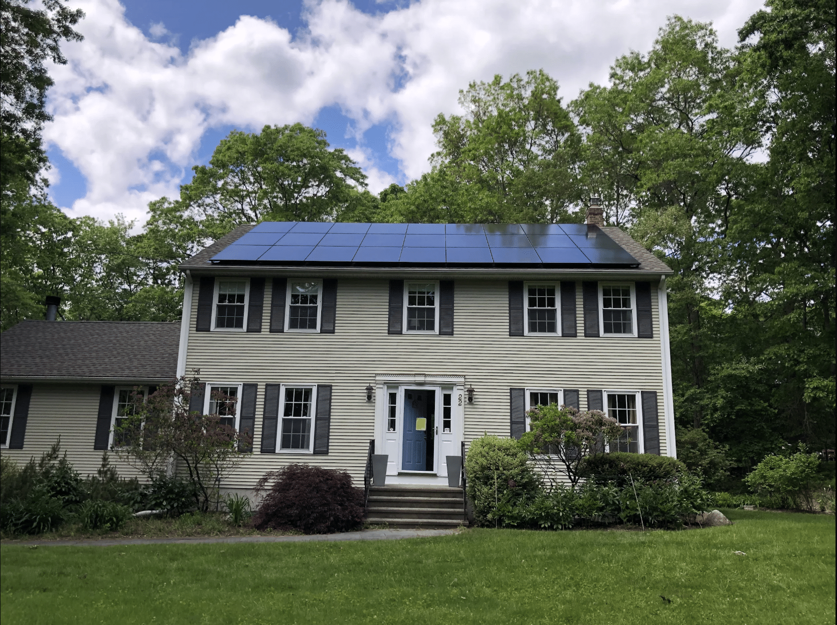 tan house with all black solar panels on a clear day in massachusetts